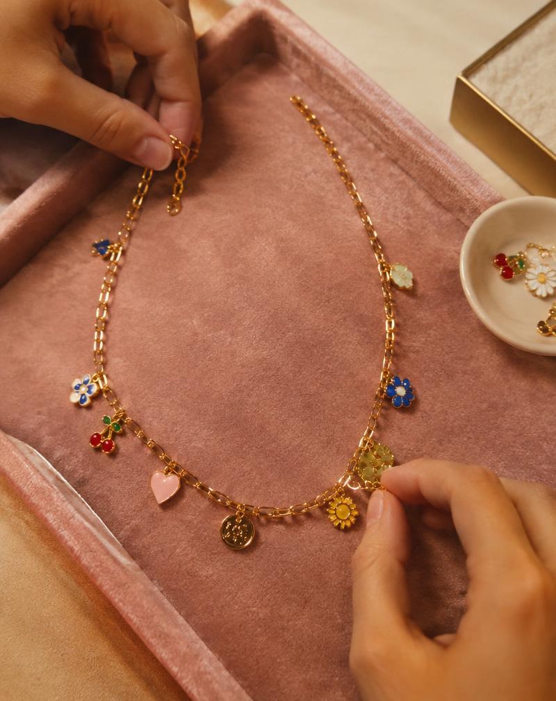 Hands building a gold charm necklace
